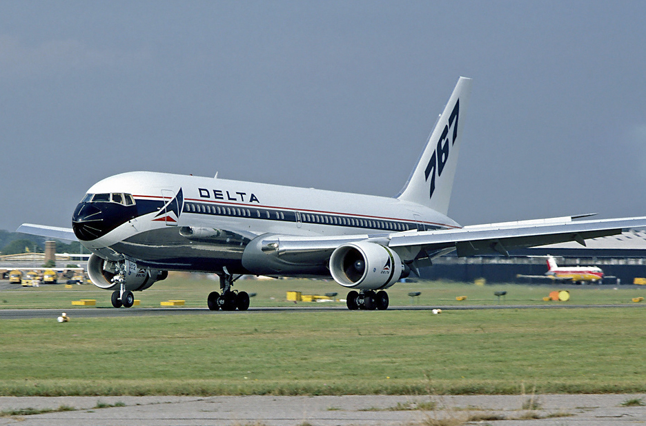 Side view of twin-engine jet touching down on runway, with deployed flaps and thrust reversers | Boeing 767-200 | Delta Airlines | N102DA | Farnborough RW25 1982